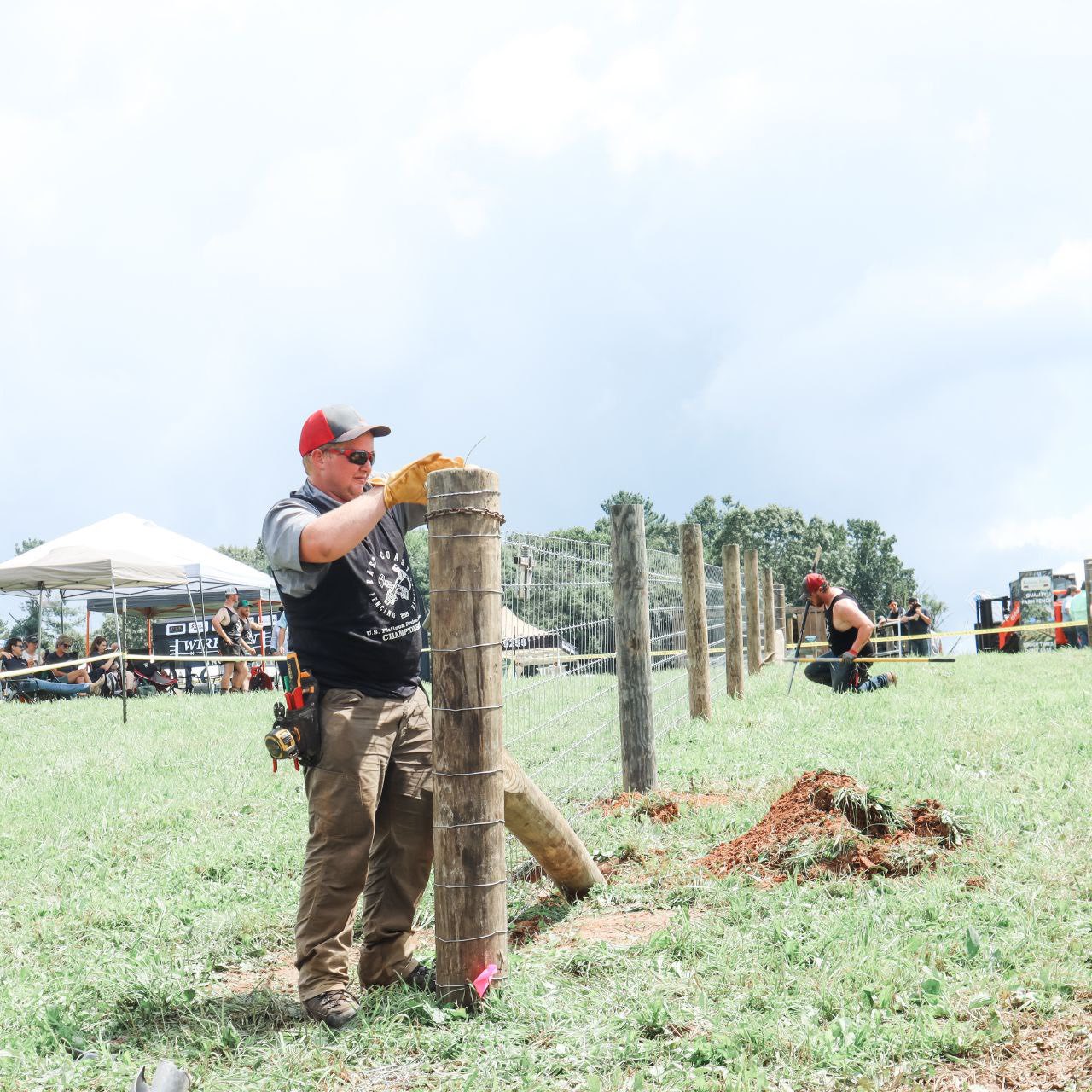 H&S crew member tying off woven wire on a wood line post