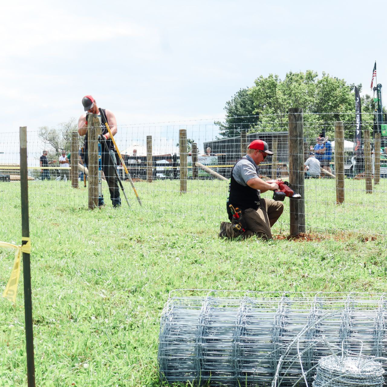 Two H&S crew members setting posts and clipping woven wire fence